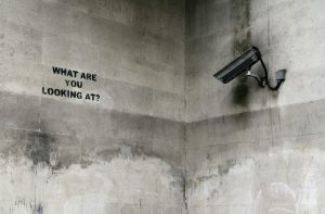 A camera watching a wall which says what are you looking at