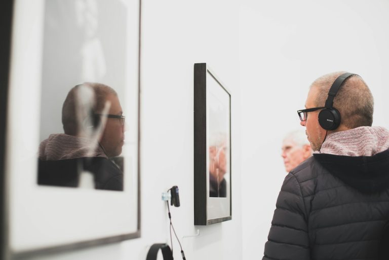 man wearing black headphone standing near the wall decor