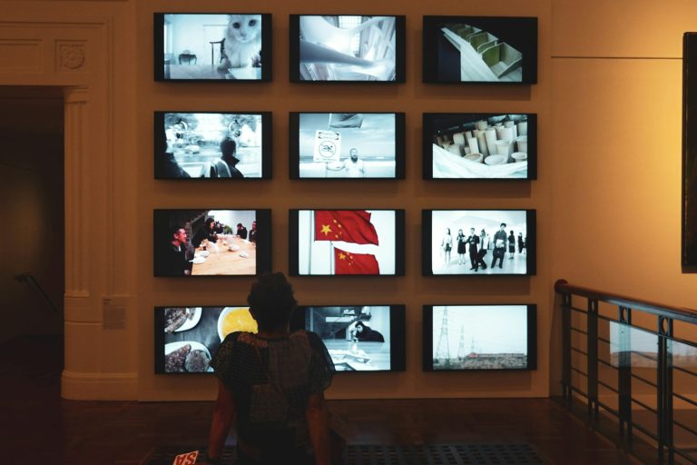 a person sitting in front of a wall of televisions