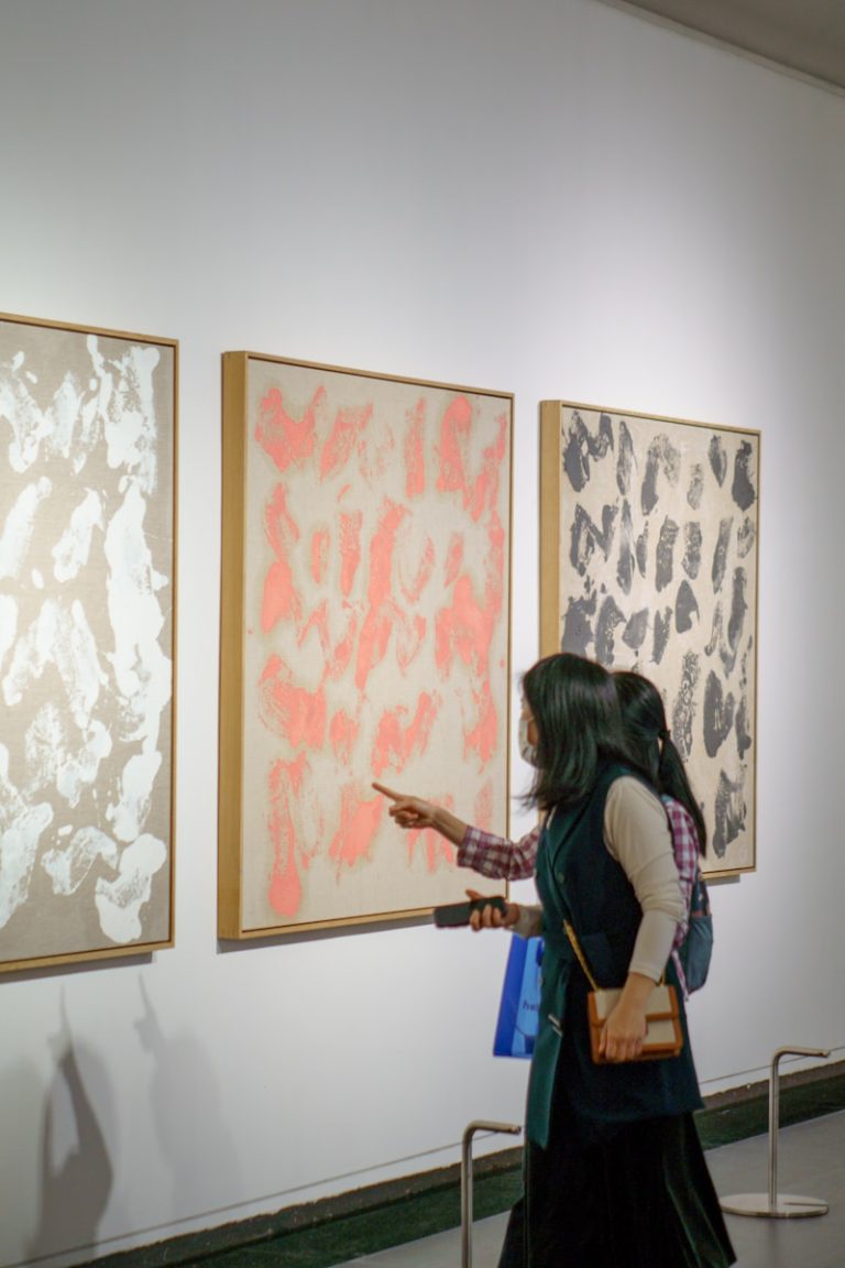 a woman looking at paintings on a wall