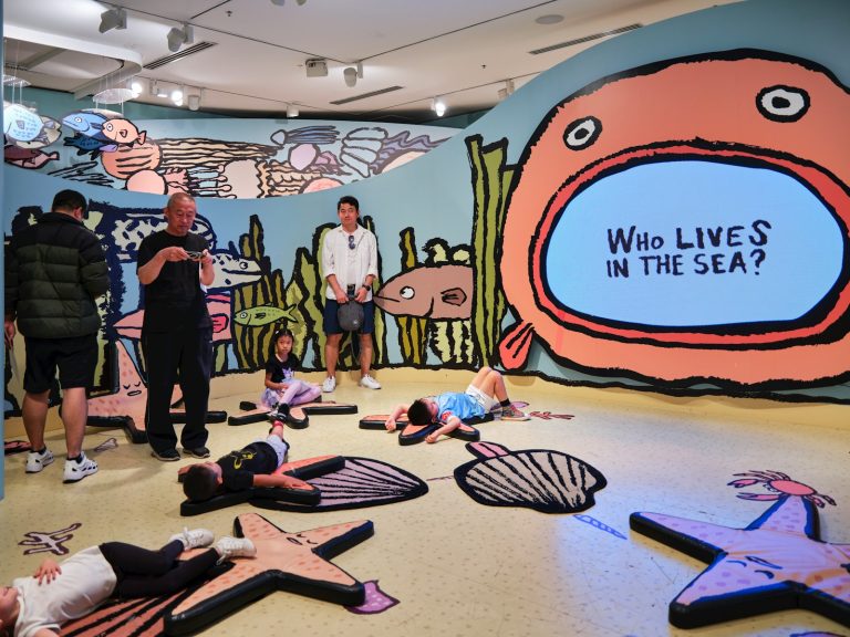 A group of people in a room with a mural on the wall